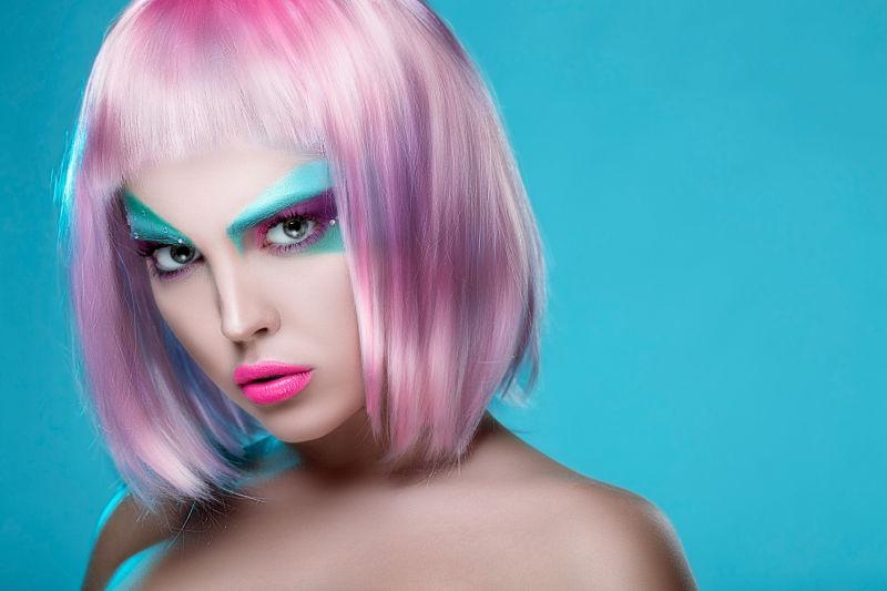 浅蓝色背景下的画着创意妆容的带着假的短发美女