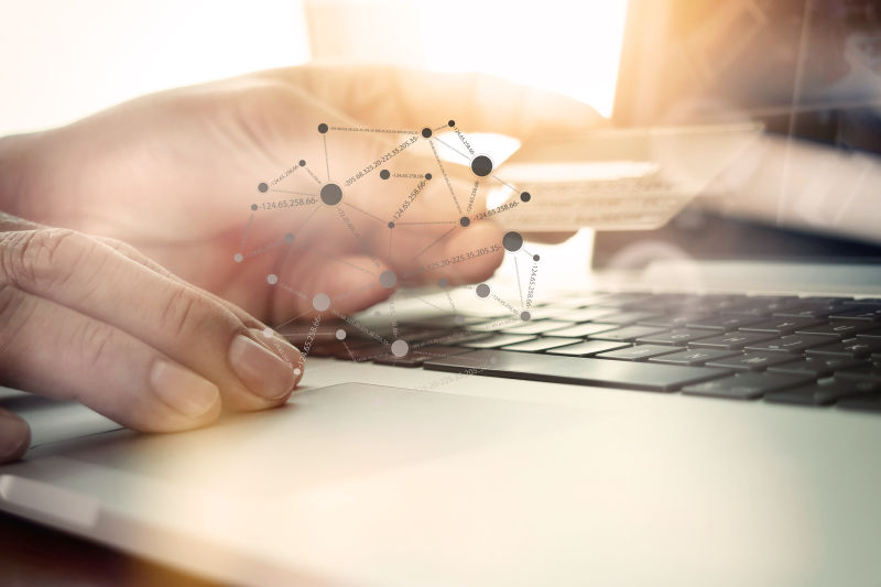 使用笔记本电脑和手持信用卡以社交媒体图作为在线购物概念