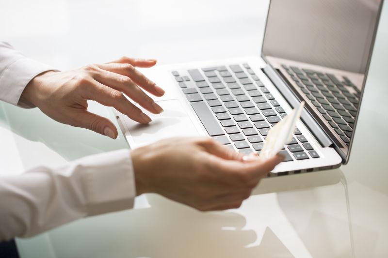 妇女使用笔记本电脑和信用卡购物