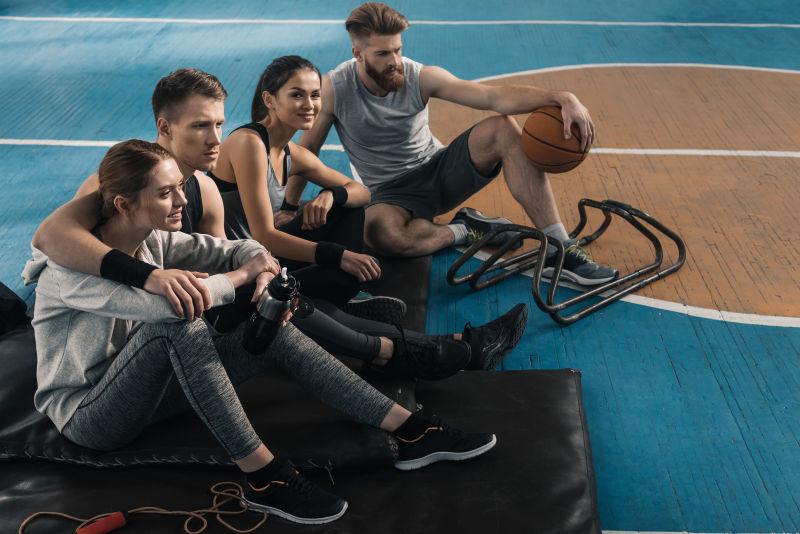 年轻的男女运动员坐在地板上