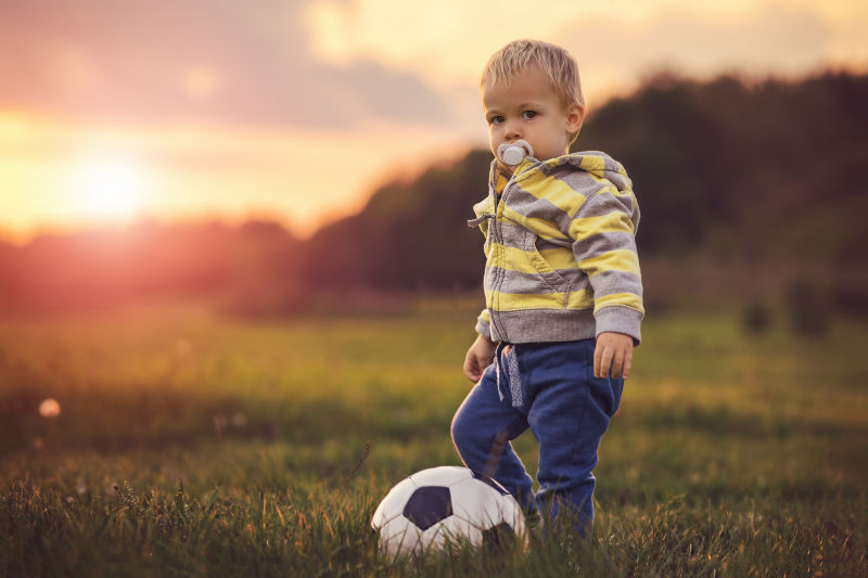 小男孩与其脚边的足球
