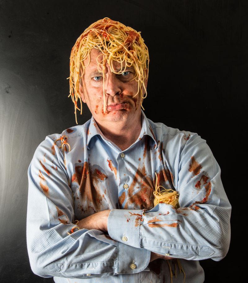 黑色背景下的头顶一些意大利面条的男人