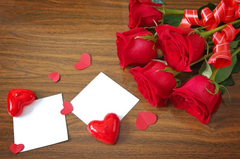 玫瑰花和心形符号系在白色空白的木桌上