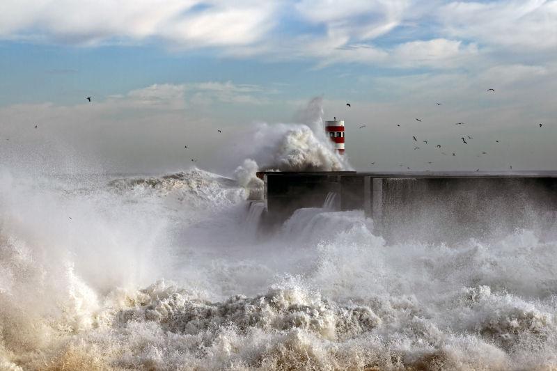 蓝色天空下灯塔码头上的海浪