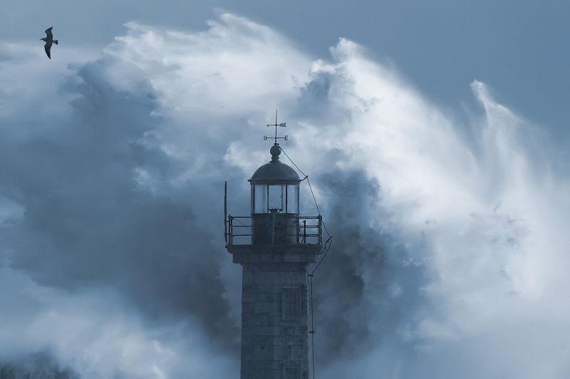 灰色天空下灯塔周围的海浪