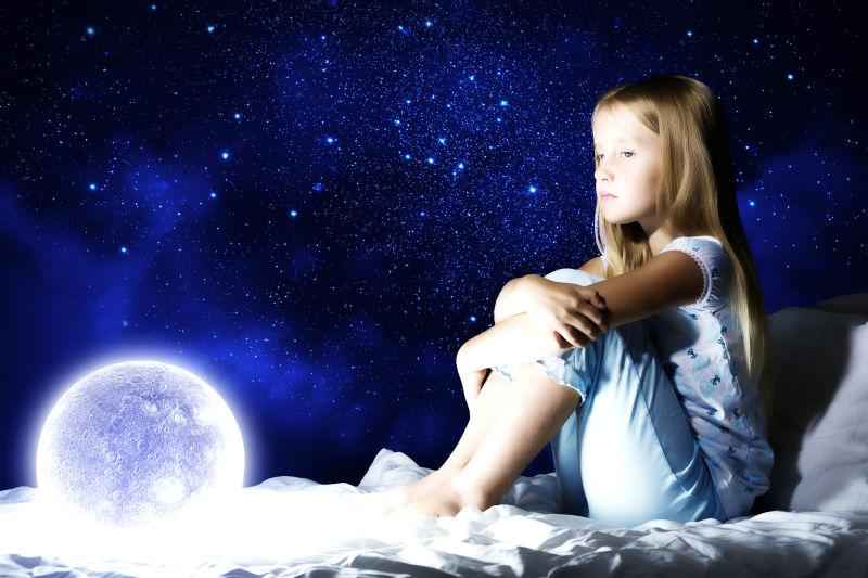 星空背景前的小女孩坐在床上