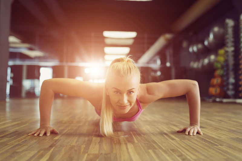 双手撑在地板上做俯卧撑的金发女人