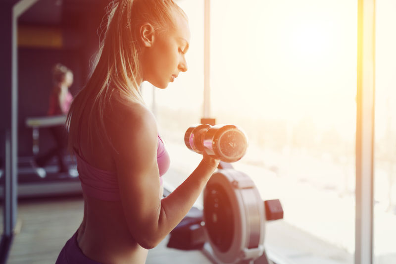 健身房里拿着哑铃锻炼的金发美女