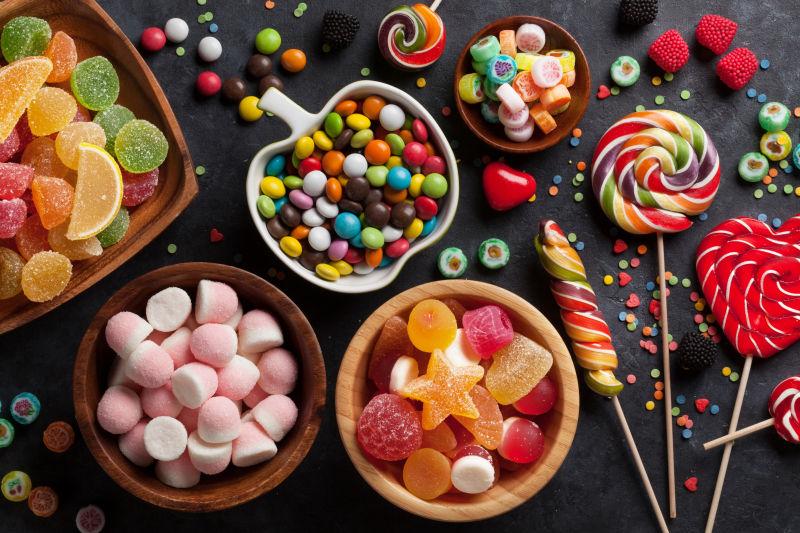 黑色桌上和各种形状的碗里的五颜六色的糖果