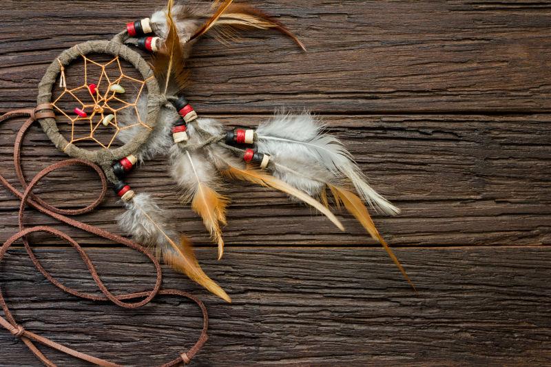木质背景上的印第安饰品羽毛捕梦网