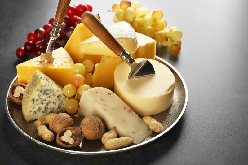 灰色背景下各种奶酪和坚果托盘