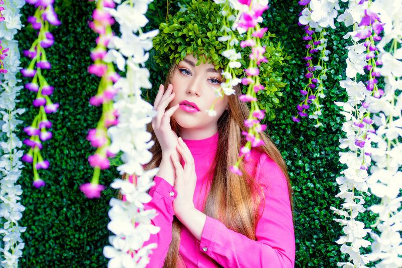 站在花藤旁边带着绿色花环的美丽女孩