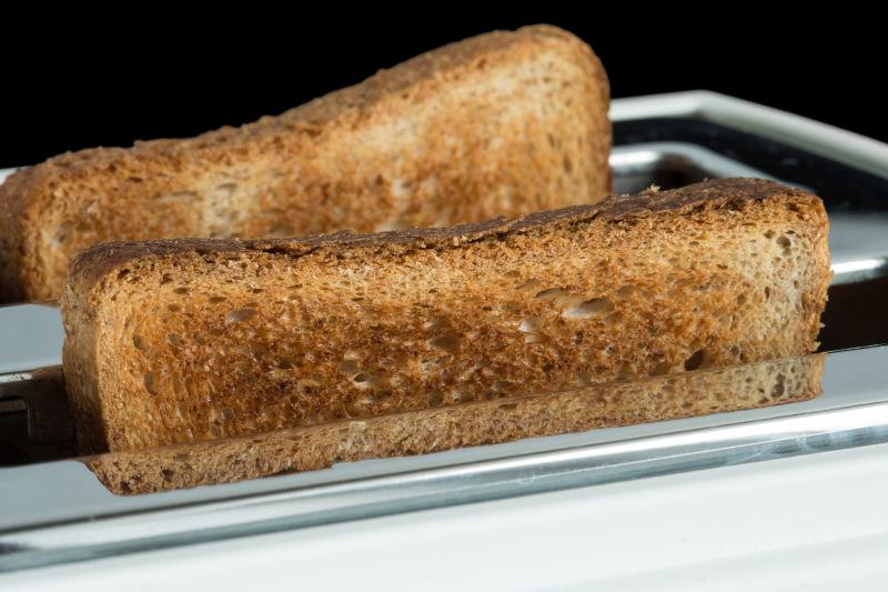 黑色背景下的烤面包和烤面包机