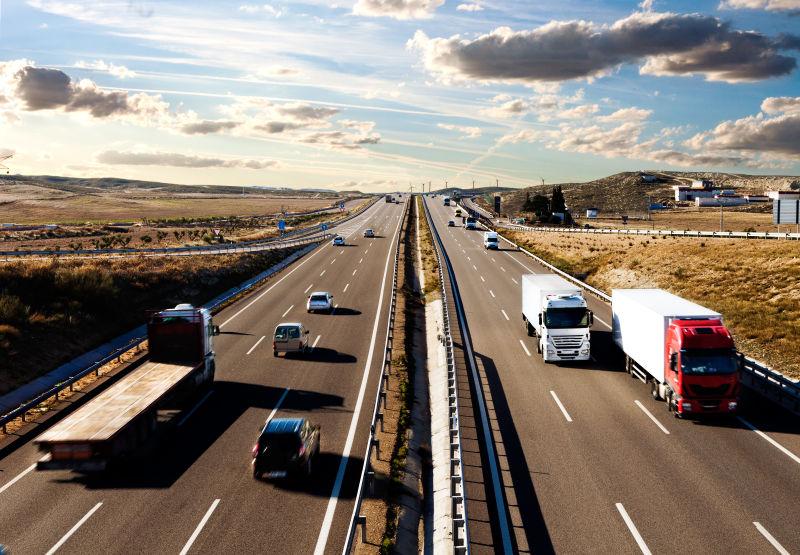 载货的卡车和汽车在公路上行驶