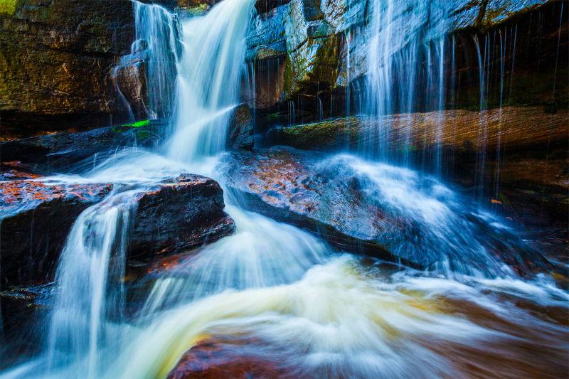 有太阳的光线的美丽森林瀑布