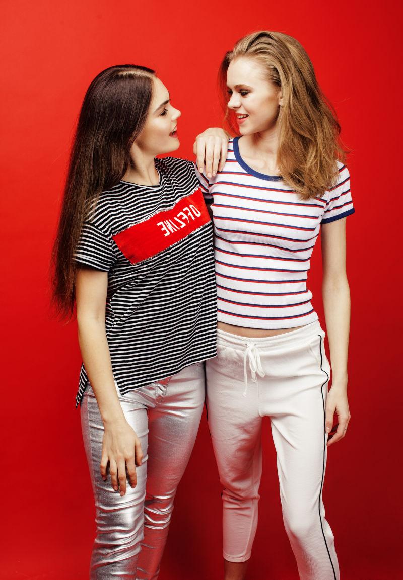 在红色背景上两个快乐的美女