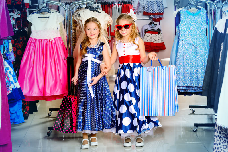 两位可爱的小女孩在童装店购物