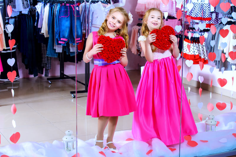 两个可爱的小女孩穿着漂亮的衣服站在橱窗前