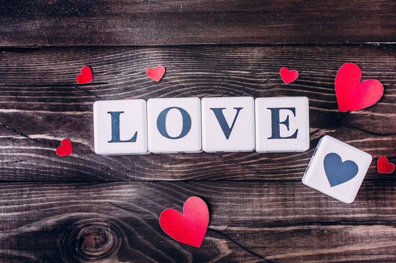 木制背景下的爱木块拼写和红色纸心