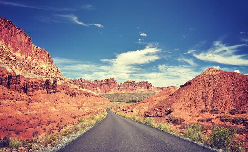 蓝天白云下群山中的老式曲线沙漠公路