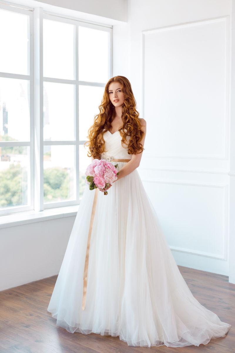 年轻漂亮的高加索人新娘在家里用白色鲜花装饰着鲜花