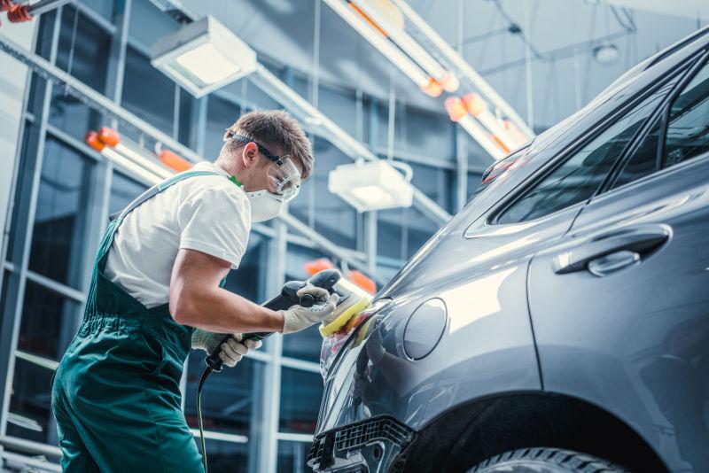 工人手拿抛光机队灰色汽车进行抛光