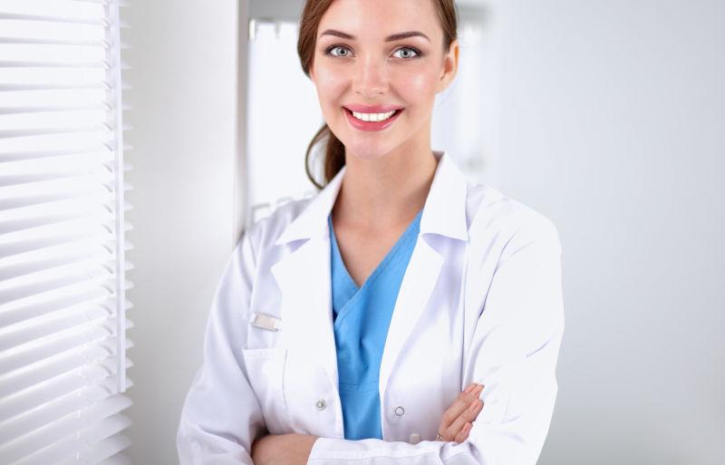 在窗户边站着的微笑的女医生