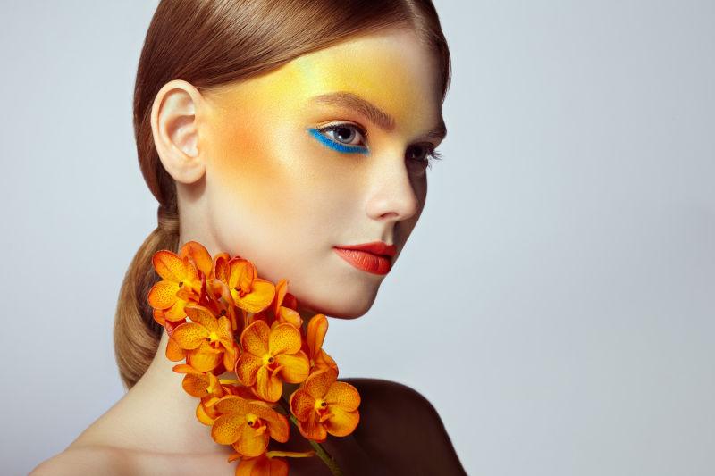 化妆眼影的美女拿着兰花