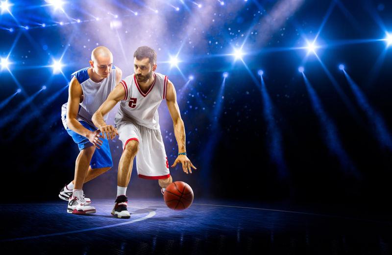 两个篮球的运动员在灯光场上表演