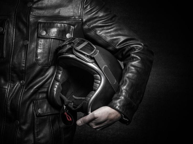 穿皮夹克的男人抱着头盔