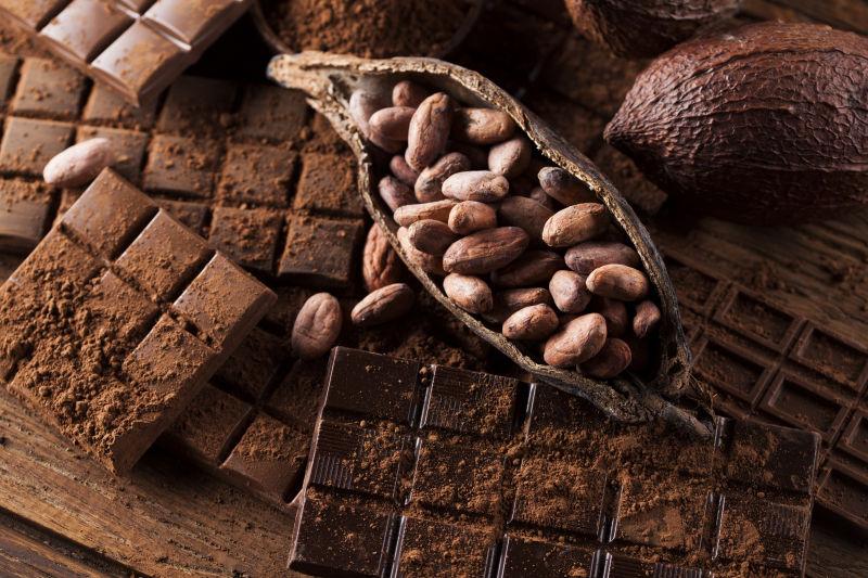 木制背景下的黑巧克力和可可豆