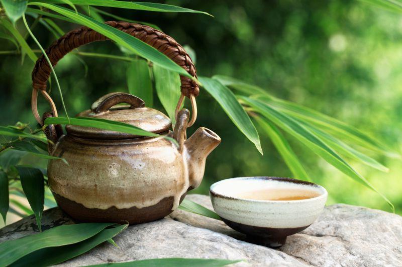 放在竹叶下石头上的茶壶和茶杯