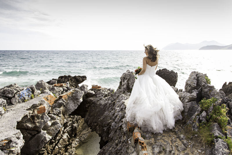站在海边悬崖上穿着白色婚纱的新娘