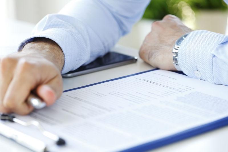 一个商人的特写镜头坐在工作站旁填写表格