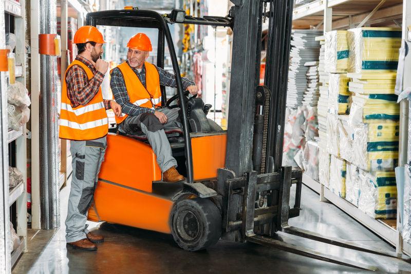 仓库中的交谈的两名叉车工人