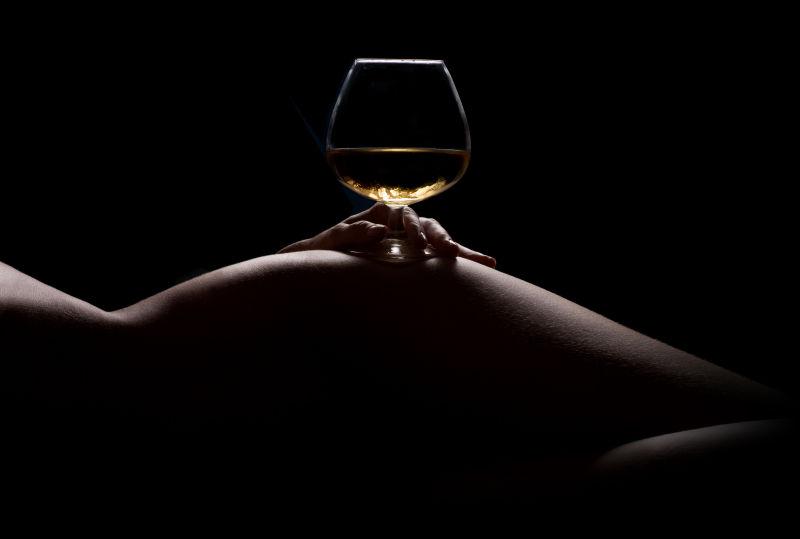 美女身上放着盛酒的高脚杯