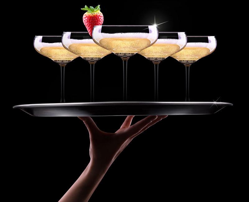 服务员在黑色背景上放香槟酒