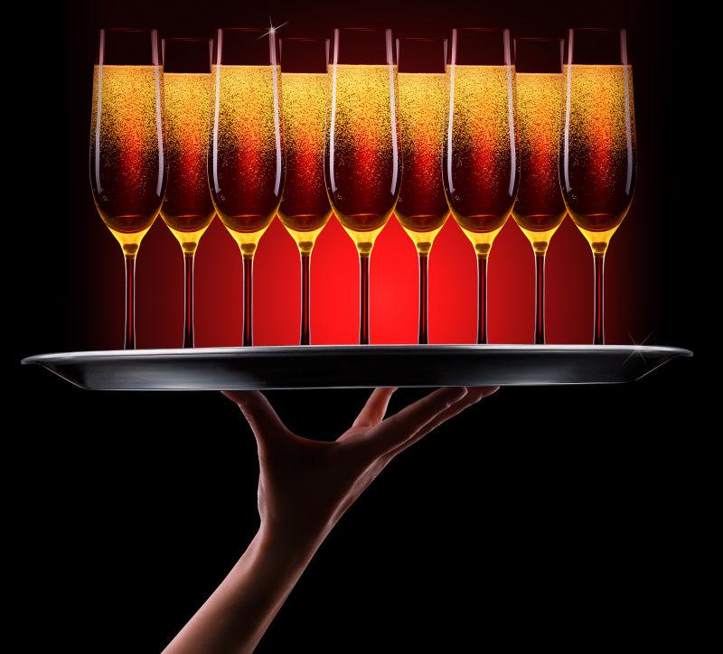 服务员在黑色背景上放着香槟酒