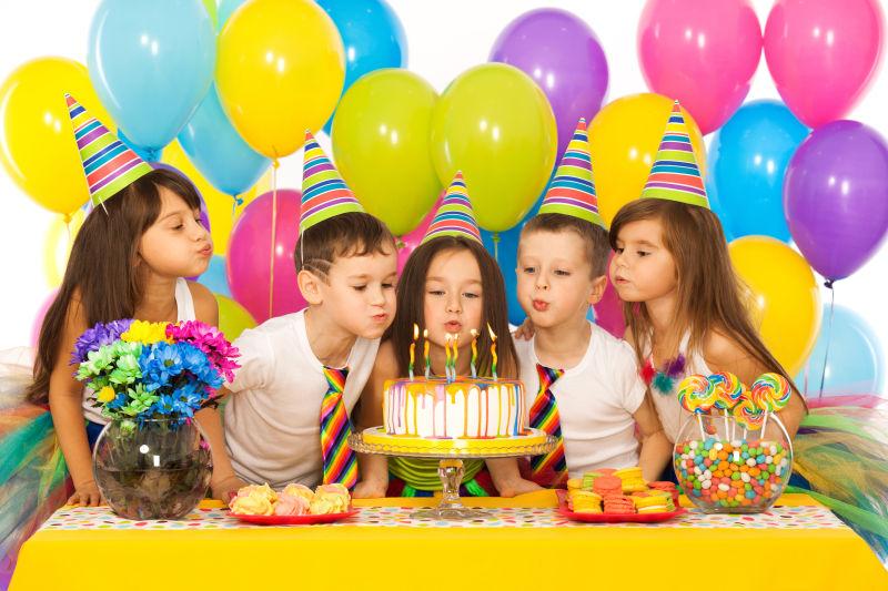 一群快乐的孩子们在蛋糕上吹蜡烛庆祝生日派对