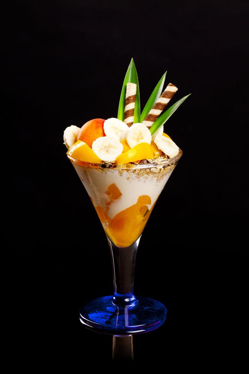 黑色背景上的鸡尾酒杯里的奶油和水果