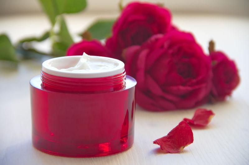 白色桌上的玫瑰和玫瑰油面霜