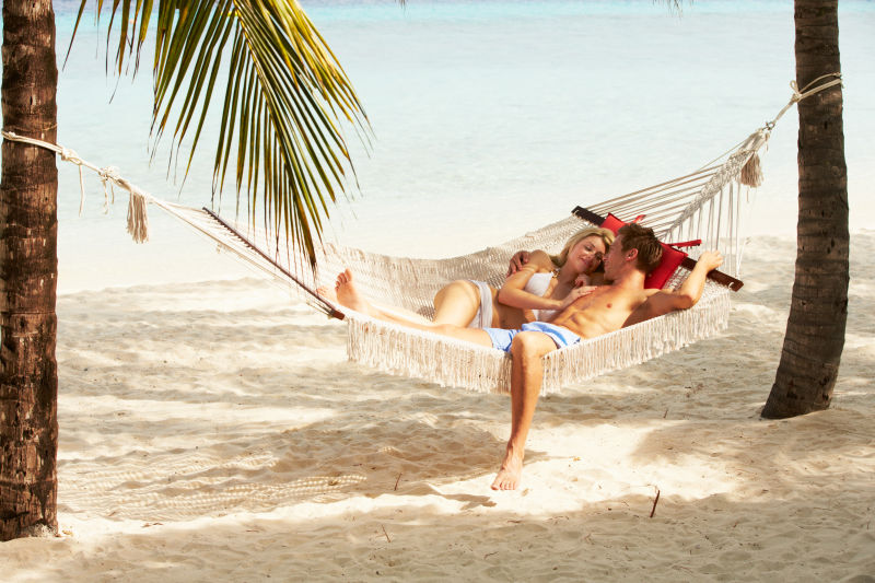 浪漫情侣在热带海滩吊床放松