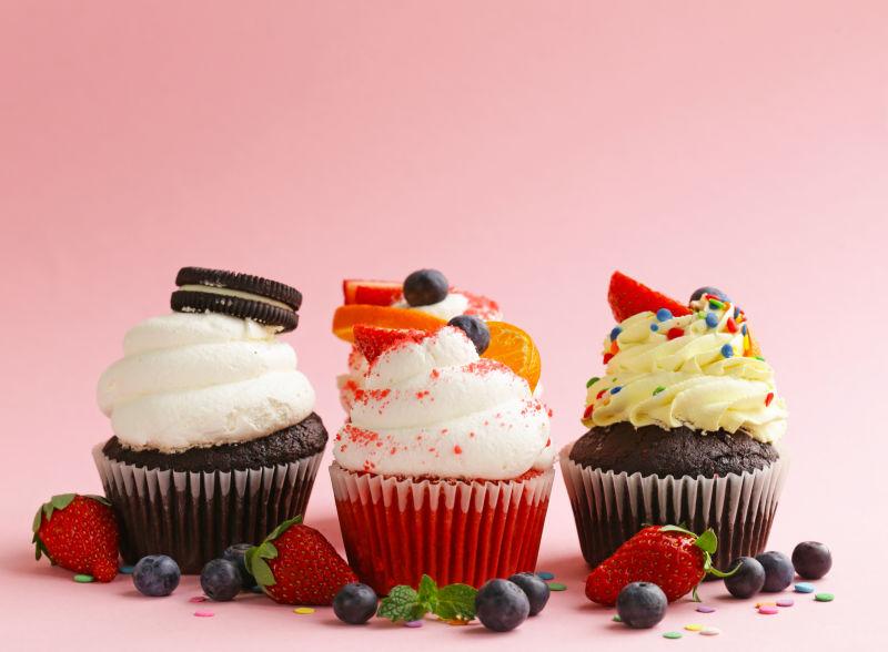 粉色背景下美味的浆果奶油蛋糕