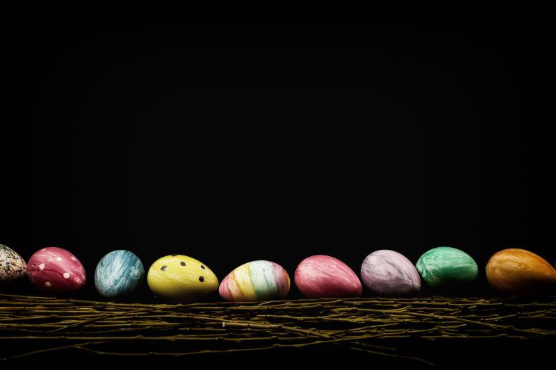 暗色背景下树枝上排成一排的复活节彩蛋