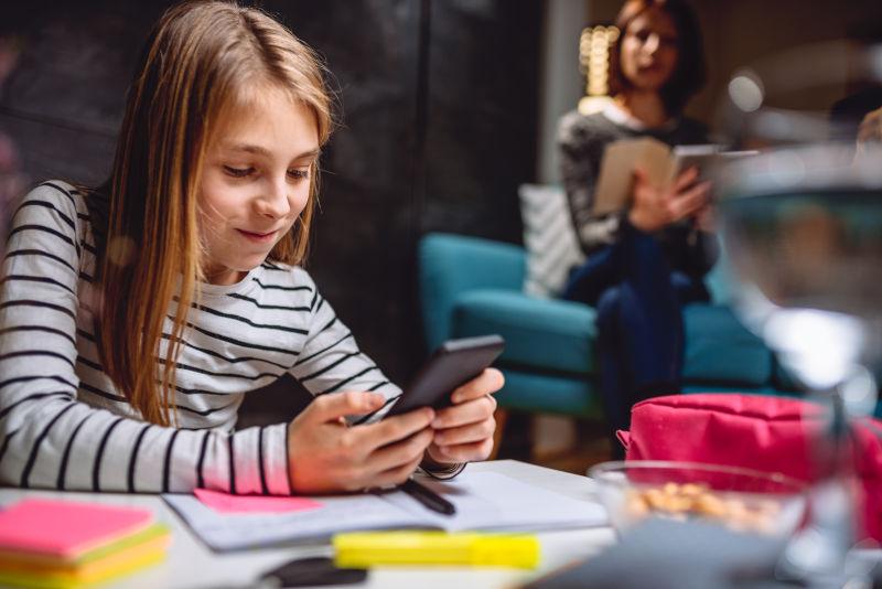 做作业和使用智能手机的女孩