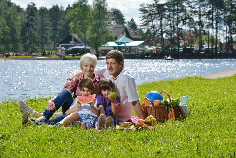 快乐的年轻家庭在户外野餐和孩子们一起吃健康食品