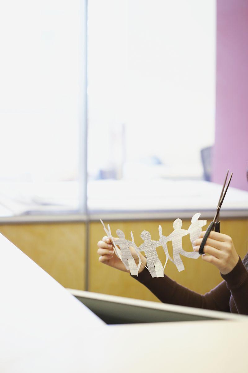 白色背景下拿着剪刀剪纸的人