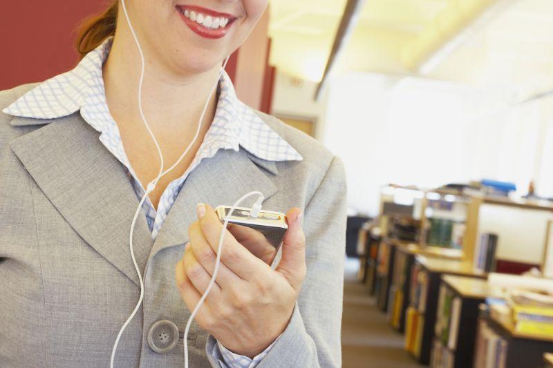 办公室里用手机听歌的微笑女人