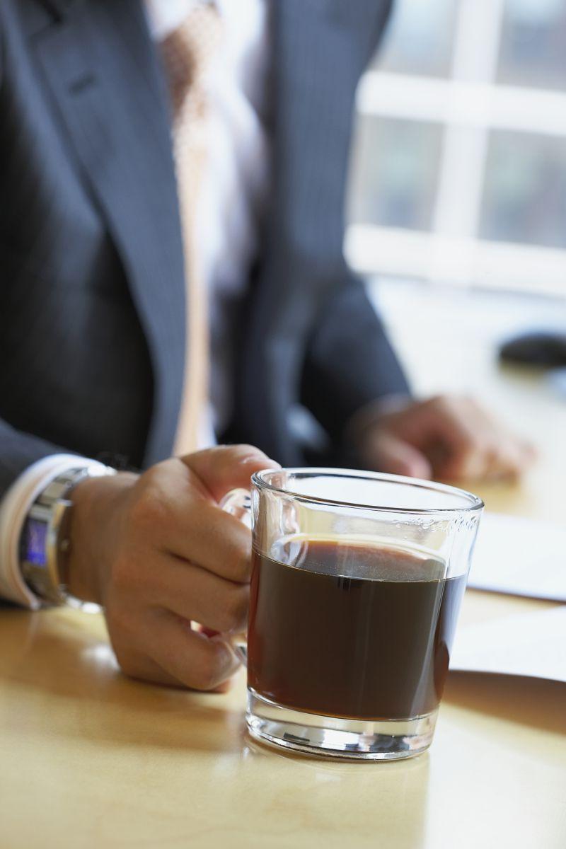 办公桌旁准备端起热饮的男人