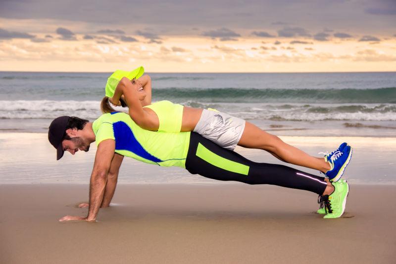 年轻的夫妇在海边练瑜伽